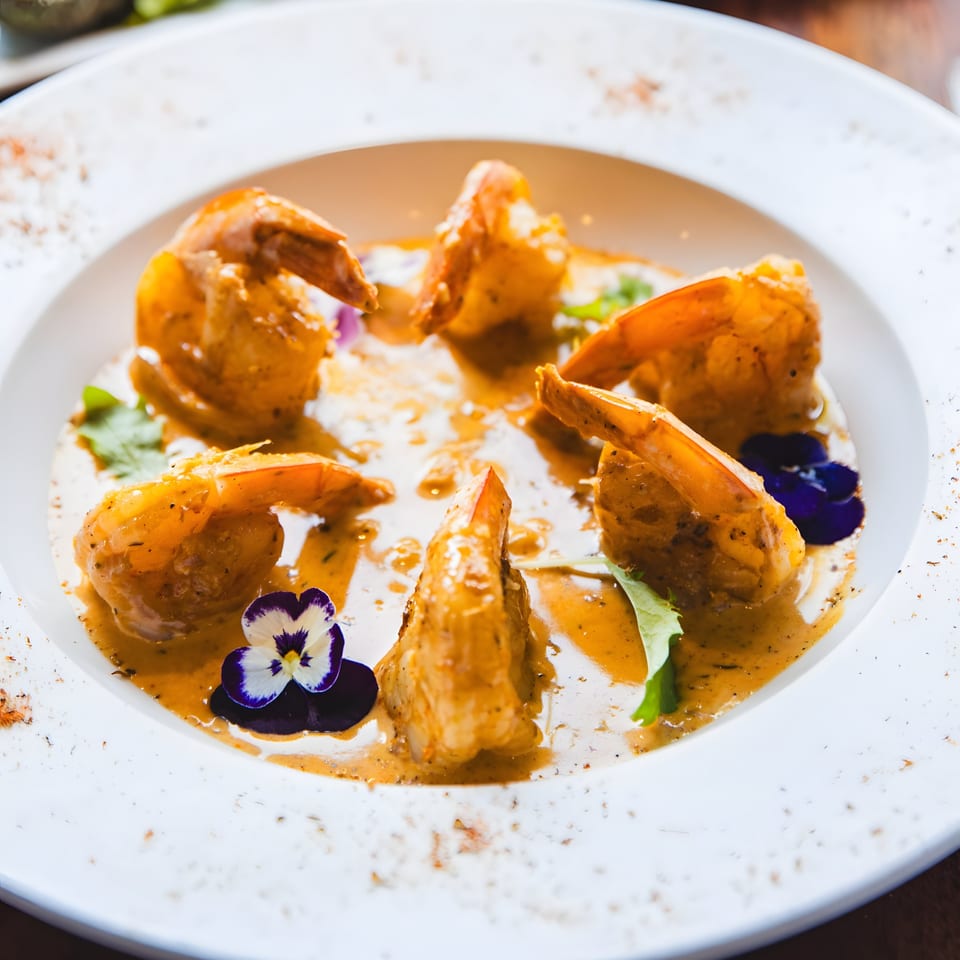 Mad Fish's shrimp dish with creamy sauce, garnished with edible flowers and herbs.